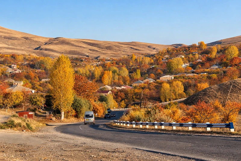 Road winding through trees with colorful autumn leaves in Armenia